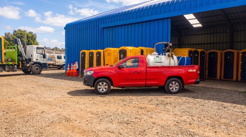 Camioneta de apoyo logístico frente a bodega con gran stock de baños químicos para arriendo en Los Ríos.